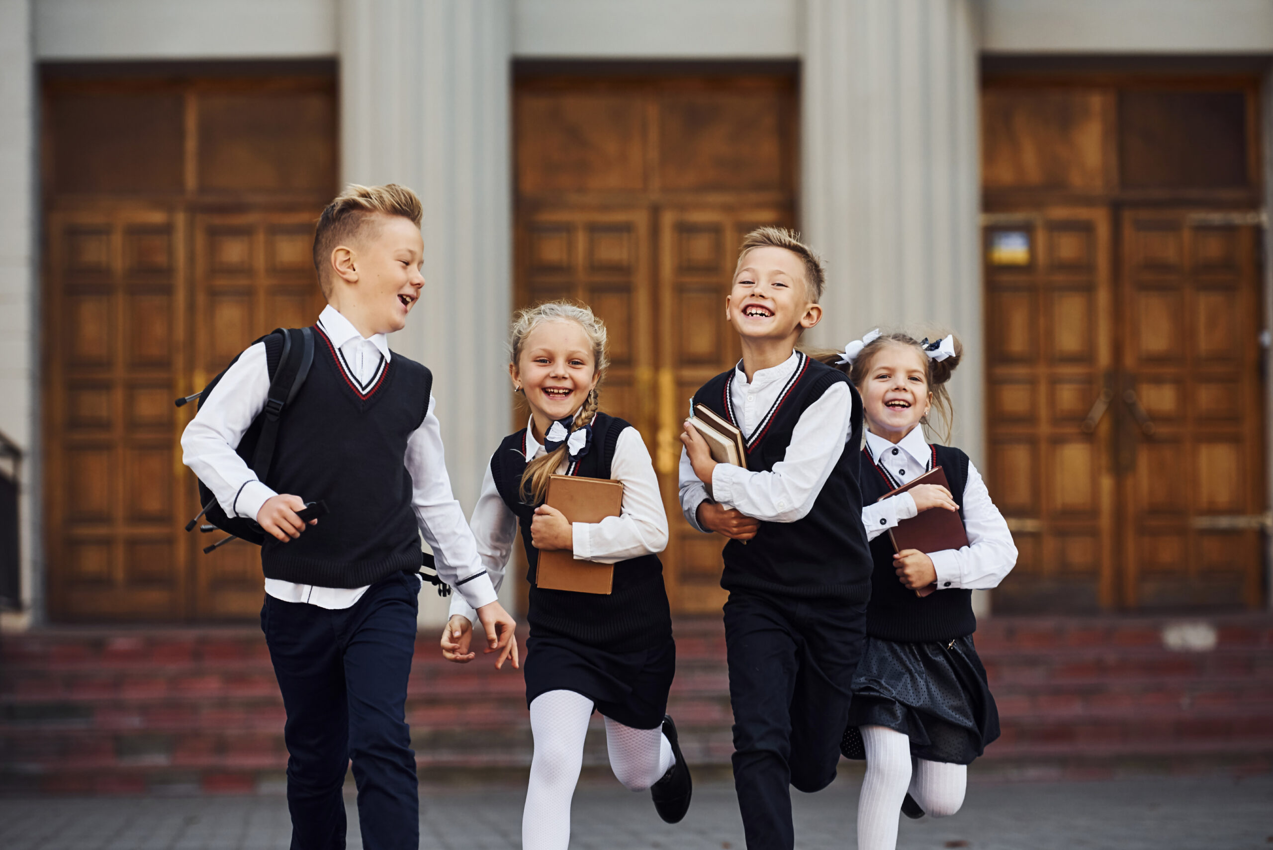 Uśmiechnięte dzieci biegnące ze szkoły