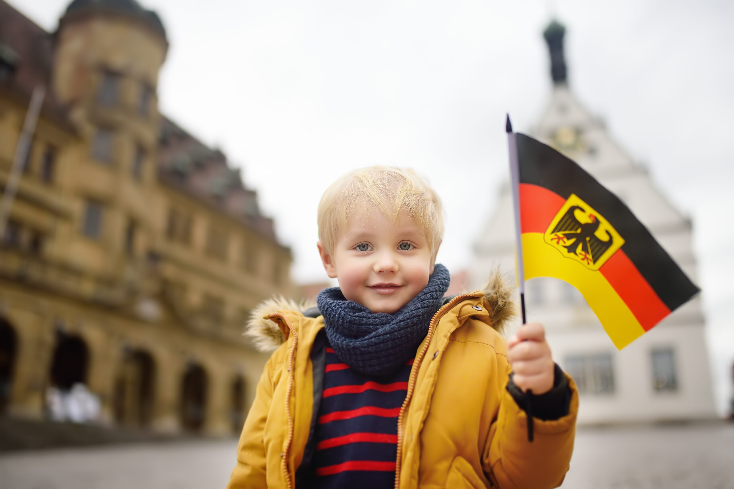 Mały chłopiec z flagą Niemiec uśmiecha się i pozuje do zdjęcia